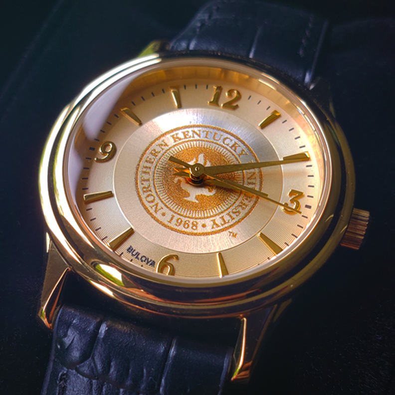 A custom golden Bulova watch with Northern Kentucky University's insignia in the center.